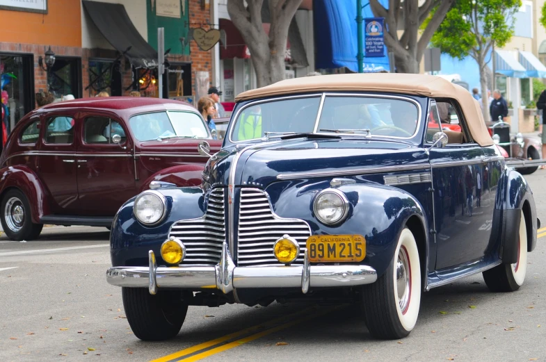 a classic car driving down a city street, a portrait, flickr, the city of santa barbara, high detail 1024, parade, 4k photo”