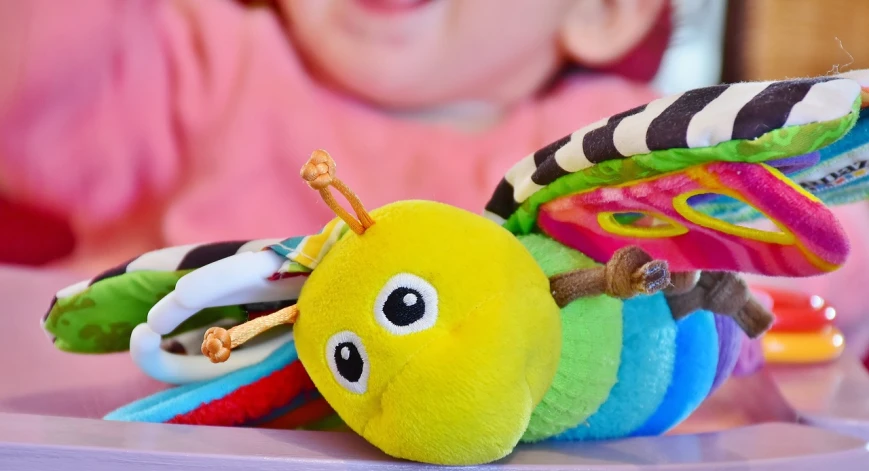 a close up of a stuffed animal on a table, inspired by Karel Appel, pexels, dragonfly-shaped, activity play centre, photo of a mechanical butterfly, cheeks