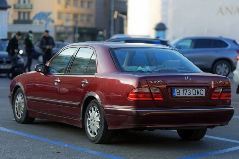 a red car is parked in a parking lot, a picture, by Andrei Kolkoutine, shutterstock, mercedez benz, late 2000’s, wine red trim, back turned