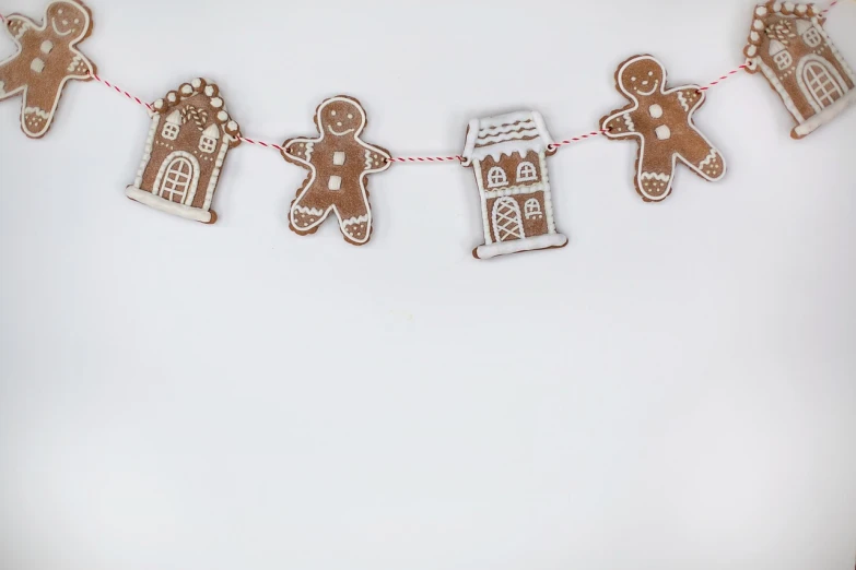 a group of gingerbreads hanging from a string, a picture, folk art, white backdrop, house, 4k high res, photo taken with sony a7r