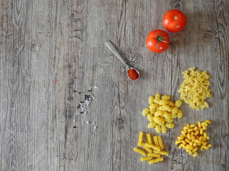 a wooden table topped with pasta and tomatoes, a still life, background image, packshot, food blog photo, corn