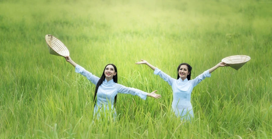 a couple of women standing on top of a lush green field, inspired by Ruth Jên, pixabay, ao dai, hands in air, 64x64, photoshoot for skincare brand