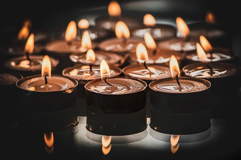 a group of lit candles sitting on top of a table, by Jesper Knudsen, pixabay, digital art, 50mm close up photography, istockphoto, remembrance, light casting onto the ground