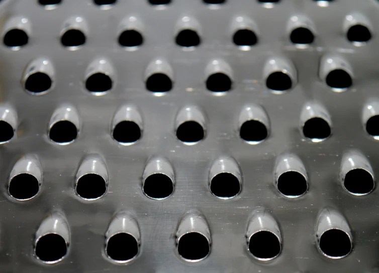 a close up of a metal grater with holes, by Jan Rustem, op art, jelly - like texture. photograph, sleek round shapes, metal floor, tubes fused with the body