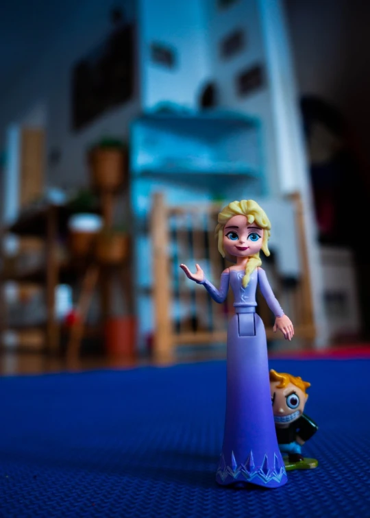 a close up of a figurine on a table, a picture, inspired by Olaf Gulbransson, unsplash, blonde - haired princess, shot on gopro9, some purple and blue, indoor shot