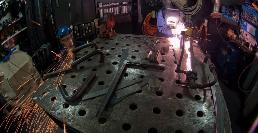 a welder is working on a piece of metal, by Matt Cavotta, flickr, assemblage, epic scale fisheye view, cinematography”, laser cut, group photo