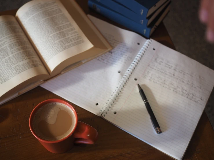 an open book sitting on top of a wooden table next to a cup of coffee, by Linda Sutton, academic art, woody\'s homework, draft, high res photo, cluttered medium shot