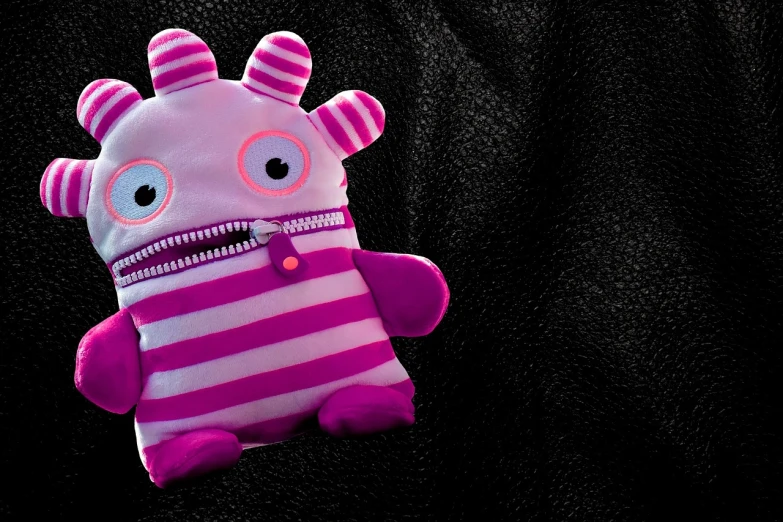 a close up of a stuffed animal on a black background, inspired by Peter Alexander Hay, graffiti, cute monster character design, purple and pink leather garments, high res photo, stripes