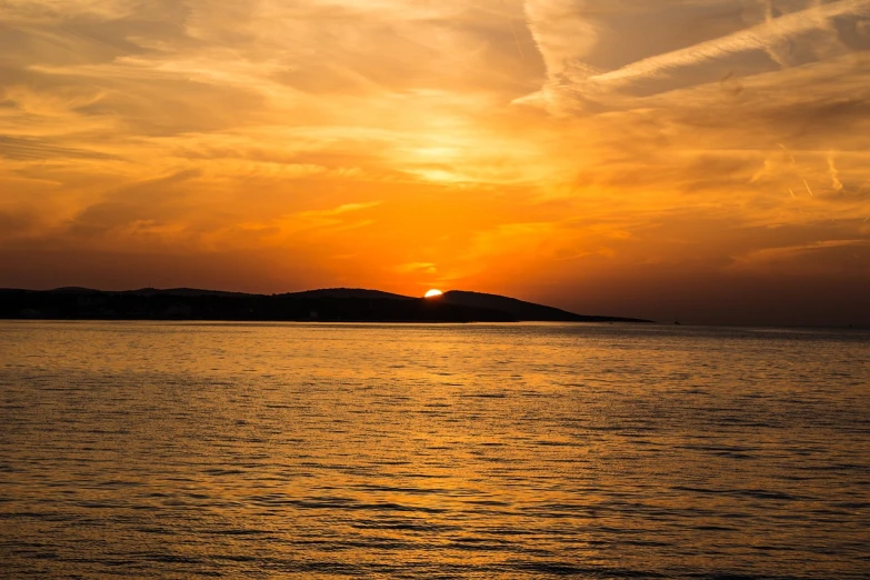 the sun is setting over a body of water, a picture, by Zoran Mušič, shutterstock, shades of gold display naturally, ibiza, orange sun set, stock photo