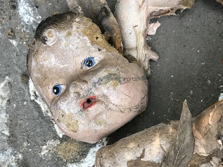 a close up of a doll with dirt on it's face, assemblage, cherub, corpses floor, nagasaki, ad image