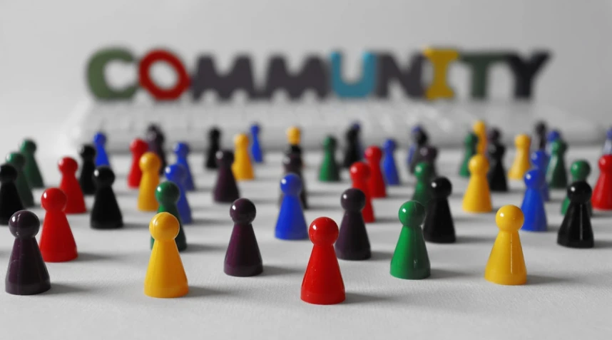 a group of people standing in front of a community sign, a photo, flickr, figurines, coloured with lots of colour, robed figures sat around a table, networking