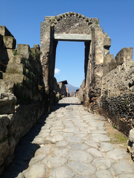 a stone walkway with a stone arch in the middle of it, by Pogus Caesar, tumblr, pompeii, 2 0 1 4, road, back towards camera
