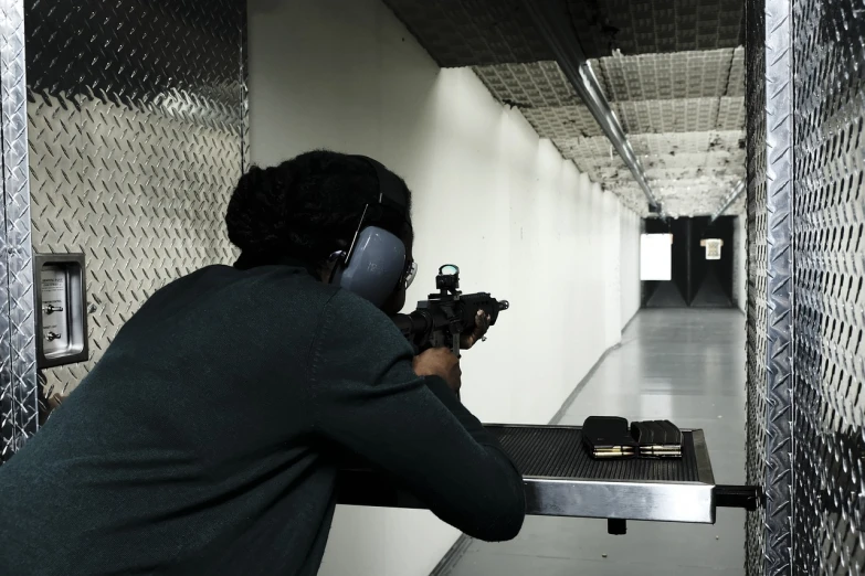 a man shooting a gun in a gun range, ebony, female, action photo, single head