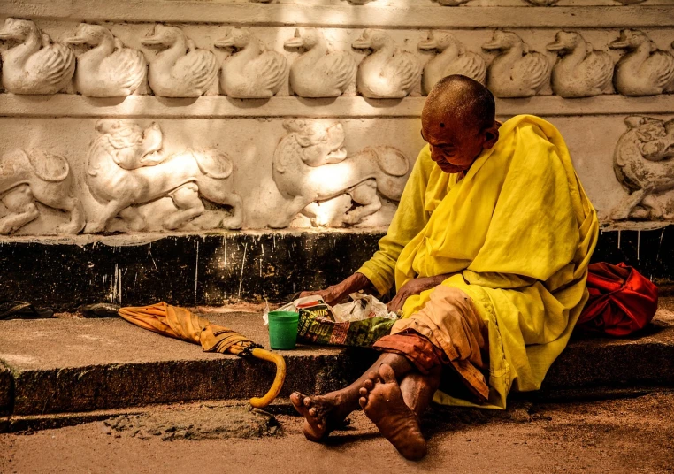 a man in a yellow robe sitting on some steps, a photo, old lady, begging for alms, indian goddess of wealth, dormant in chains