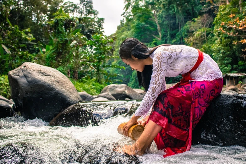 a woman is washing her feet in a river, inspired by Fernando Amorsolo, pexels contest winner, sumatraism, traditional dress, pretty girl, white water, with a red skirt