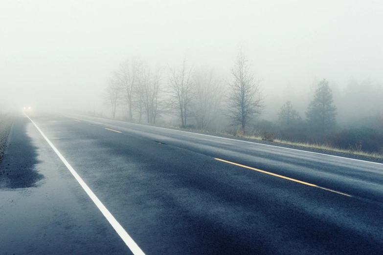 a road on a foggy day with trees in the background, postminimalism, wet highway chase, eerie shimmering surroundings, no text!, barely visible