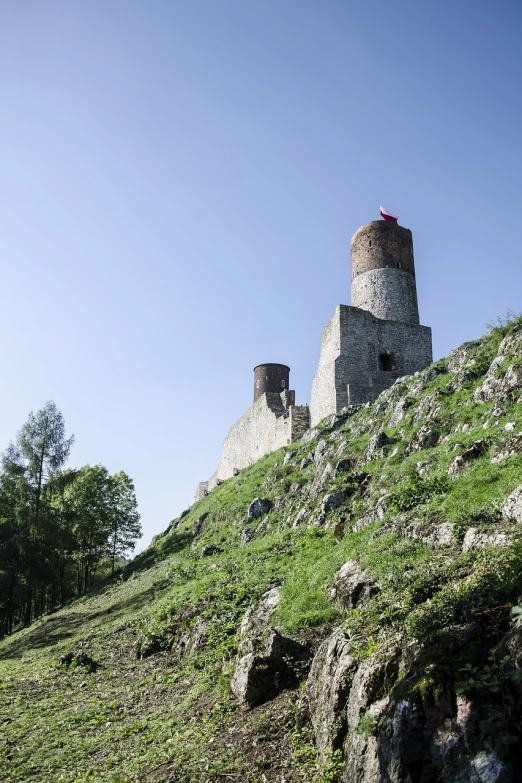 a stone tower sitting on top of a lush green hillside, by Walenty Wańkowicz, shutterstock, two towers, zdzislaw bekinski, destroyed castle, low angle view