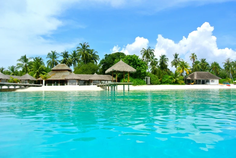 a group of huts sitting on top of a sandy beach, a picture, shutterstock, sumatraism, tropical pool, wallpaper - 1 0 2 4, island in a blue sea, tropical undertones