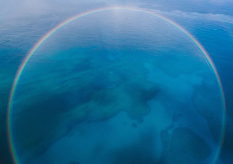 a rainbow in the sky over a body of water, by Jan Rustem, mariana trench, high angle close up shot, ultra wide lens, helicopter view