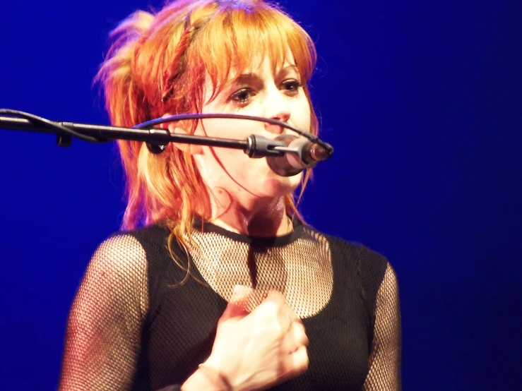 a woman with red hair singing into a microphone, by Heather Hudson, flickr, crystal castles, her hair is in a pony tail, netting, mylene farmer
