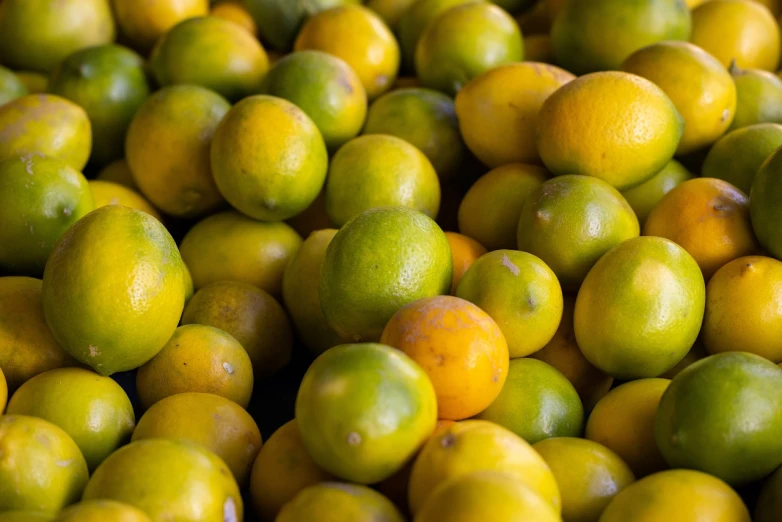 a pile of lemons sitting on top of each other, a picture, by Dietmar Damerau, bright green dark orange, colors of jamaica, very shallow depth of field, high quality product image”
