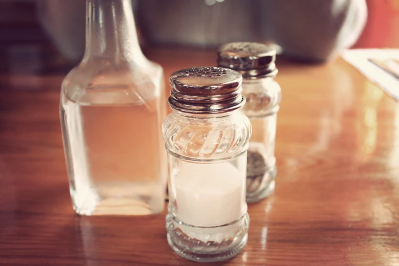 salt and pepper shakers on a wooden table, a picture, unsplash, bottles covered in wax, crisp photo, diner, clear glass