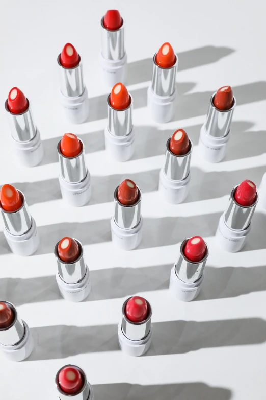 a group of red and white lipstick on a white surface, inspired by Luma Rouge, bauhaus, orange and white color scheme, ji-min, multiple lights, lots of sunlight