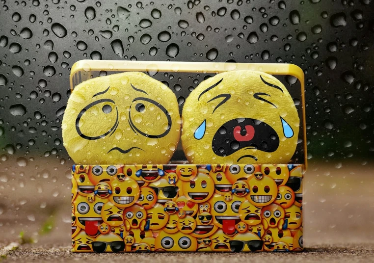 a couple of yellow emoticions sitting on top of a box, rain drops on face, case, high quality product image”, face showing