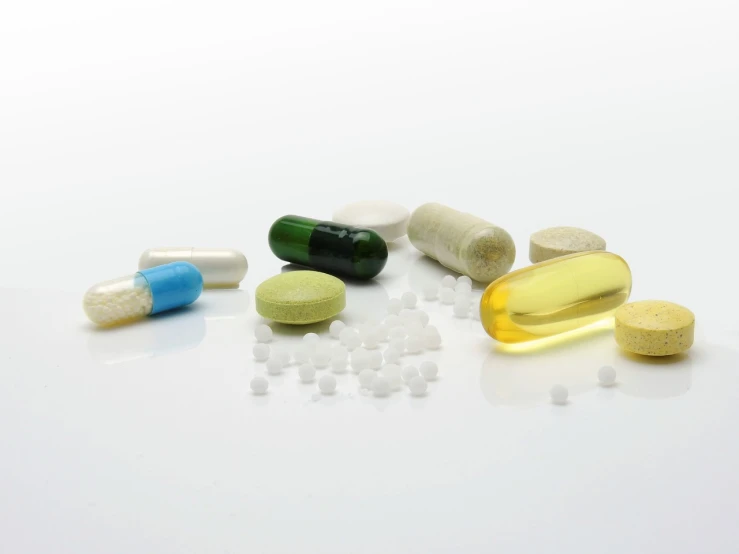 a variety of pills and capsules on a white surface, a picture, close-up product photo