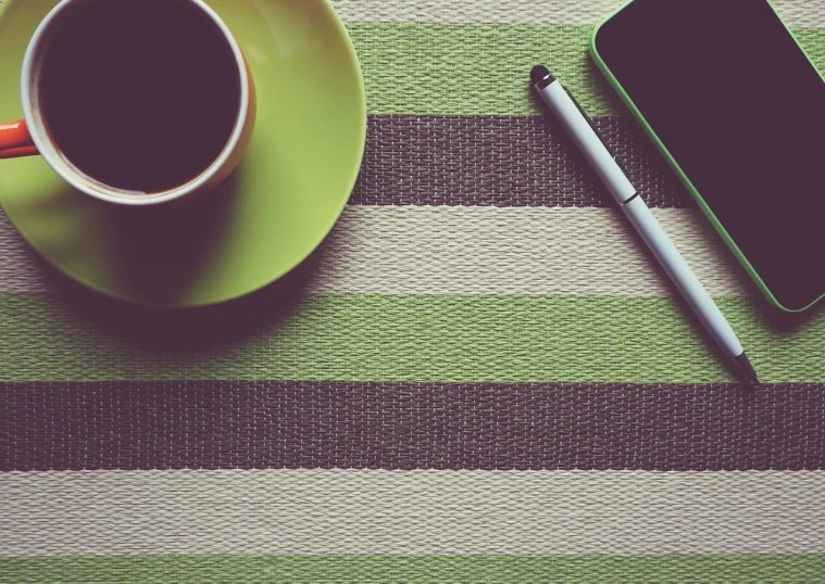 a cup of coffee next to a cell phone, minimalism, green and black colors, tablecloth, vintage retro colors, carpet