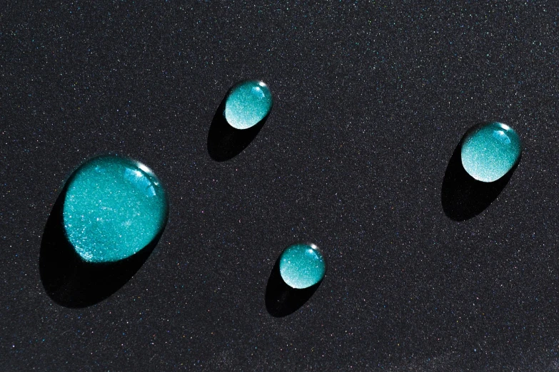 a group of blue stones sitting on top of a black surface, a microscopic photo, inspired by Lucio Fontana, minimalism, dew drops, teal sky, shiny gloss water reflections, shot with sony alpha 1 camera