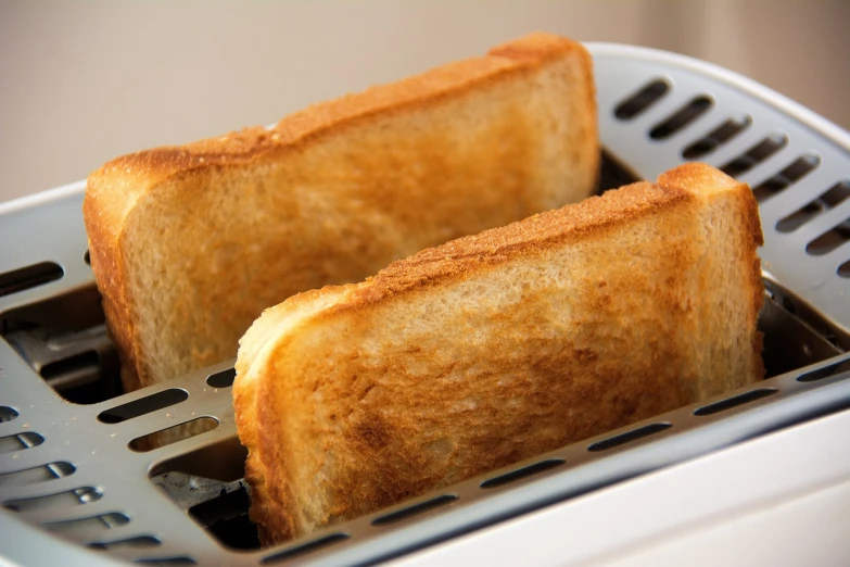 two pieces of toast sitting in a toaster, a picture, pixabay, bright sunlight, detailed zoom photo, istock, brawny