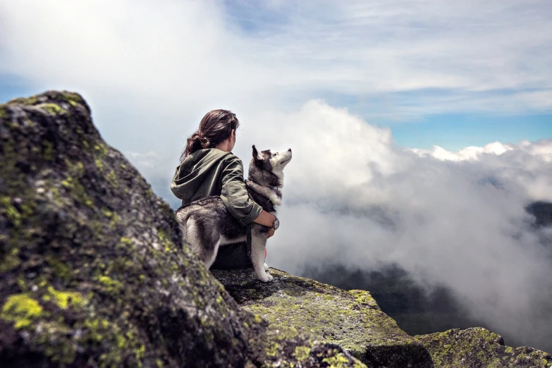 a woman sitting on top of a mountain with a dog, by Emma Andijewska, unsplash, siberian husky, upon the clouds, avatar image, sakimichan