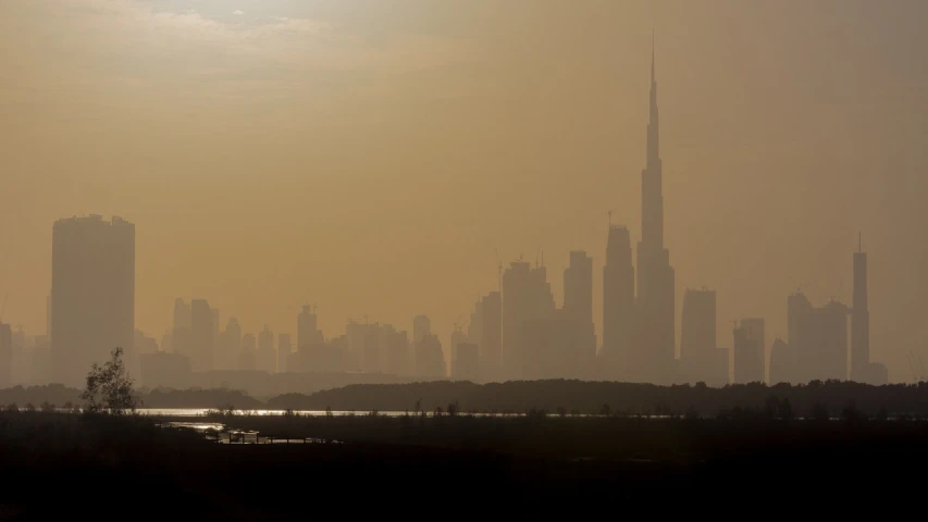 a large body of water with a city in the background, by David Budd, shutterstock, hurufiyya, the sun's rays through the dust, dubai, silhouetted, tall spires