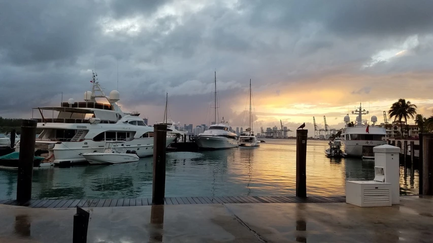 a marina filled with lots of boats under a cloudy sky, by Robbie Trevino, hurufiyya, eighties miami vice, watching the sunset, rainy evening, 4 k post