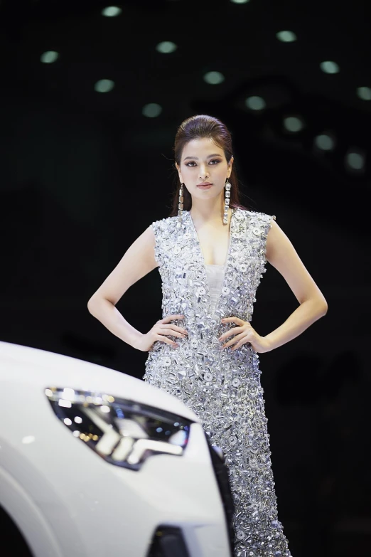 a woman standing next to a white car, inspired by Liu Haisu, happening, wearing silver dress, fashion show photo, beautiful south korean woman, shiny and sparkling