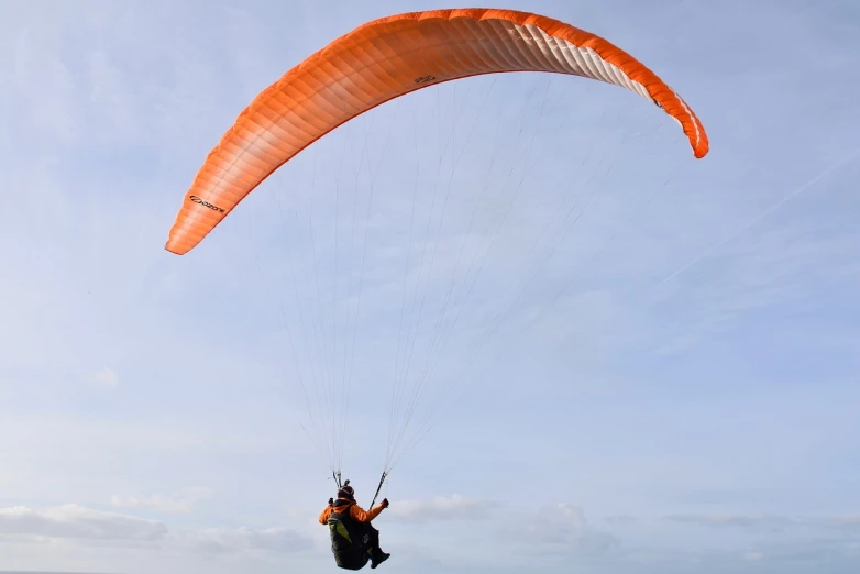 a person that is in the air with a parachute, by Dave Allsop, shutterstock, taken with a pentax1000, an orange, fine wind, including a long tail