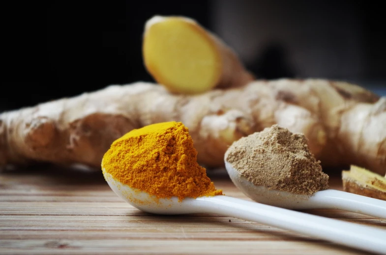 a couple of spoons sitting on top of a wooden table, ginger, shades of gold display naturally, powder, eating