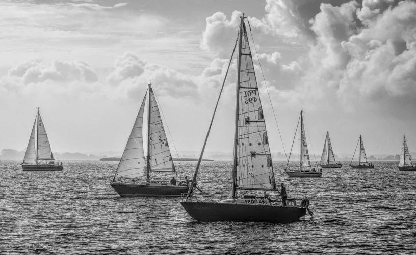 a group of sailboats floating on top of a body of water, a black and white photo, by Jan Pynas, pixabay contest winner, fine art, sports photography, stunningly detailed, 38mm photograhpy, having a good time