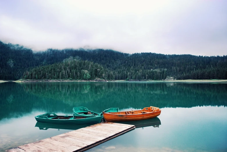 a couple of boats sitting on top of a lake, a picture, by Alexander Bogen, pexels, minimalism, teal and orange colors, dark emerald mist colors, whistler, istock