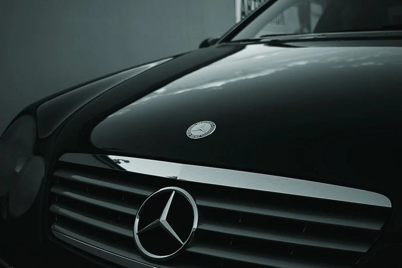 a close up of a mercedes logo on a car, by Thomas Bock, pexels contest winner, minimalism, taken on a 1990s camera, wrapped in black, good looking face, [ [ hyperrealistic ] ]