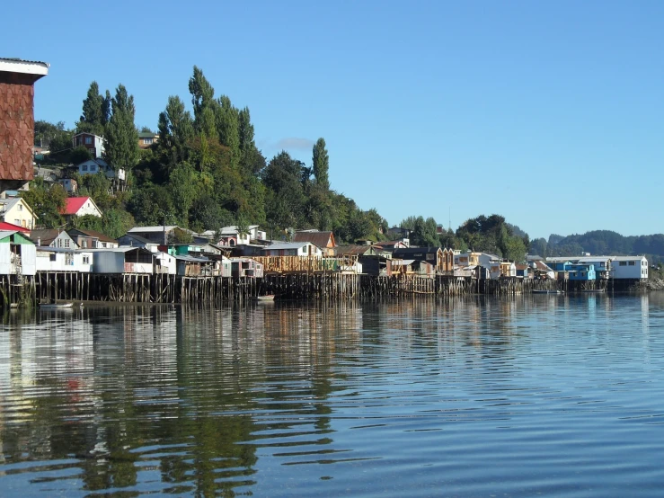 a large body of water filled with lots of houses, a picture, by Joseph Pickett, flickr, hurufiyya, chile, houses on stilts, moored, shiny skin”