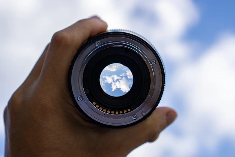 a close up of a person holding a camera lens, a picture, by Jan Rustem, art photography, through clouds blue sky, professional foto, looking through a portal, short telephoto