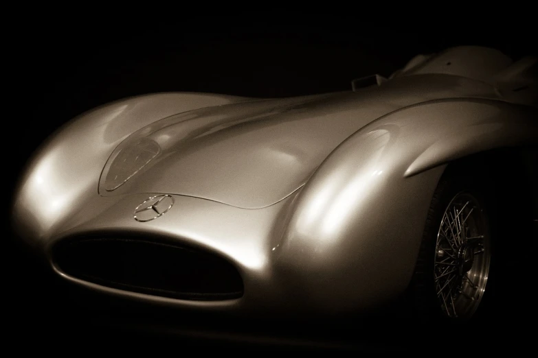 a black and white photo of a silver sports car, inspired by Peter Basch, soft golden light, mercedes, sepia toned, curving