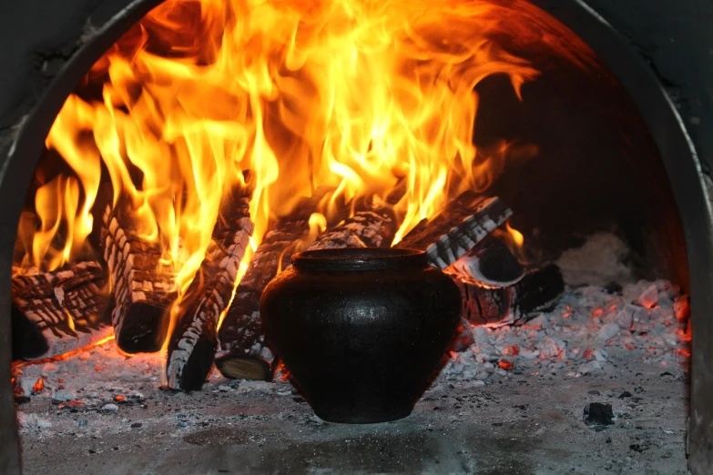 a black pot sitting in front of a fire, by Arthur Sarkissian, pixabay, hurufiyya, orthodox, energy flows of water and fire, restaurant, porcelain