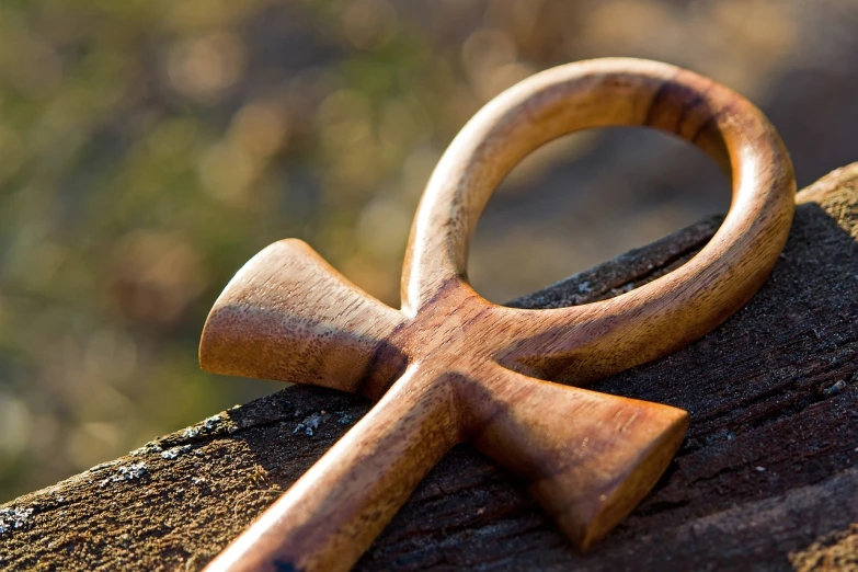 a wooden cross sitting on top of a piece of wood, by Bernard Meninsky, symbolism, the key of the nile, infinity symbol like a cat, god is a woman, beautiful image