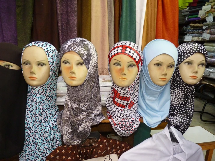 a group of mannequin heads sitting next to each other, hurufiyya, hijab, patterned scarf, with serious face expression, orthodox