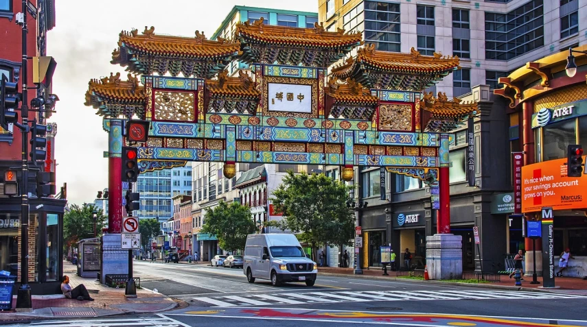 a car driving down a street next to tall buildings, a photo, by Douglas Shuler, shutterstock, cloisonnism, centered torii gate, washington dc, chinatown bar, 1683