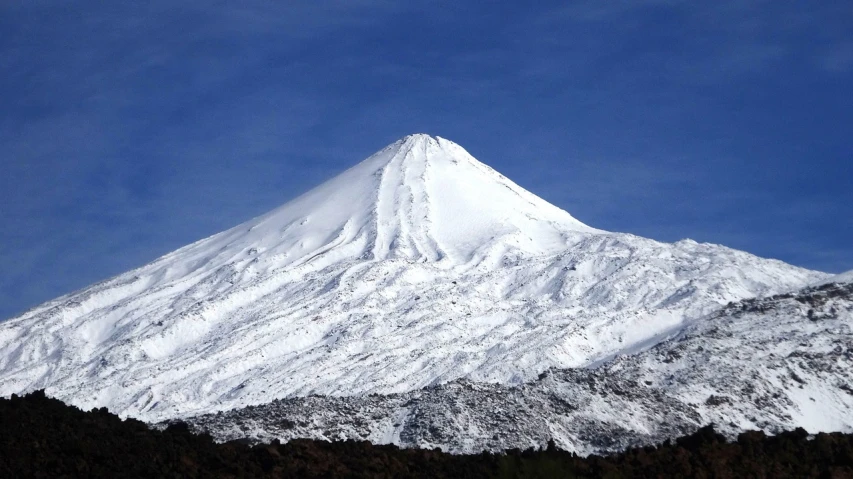 a snow covered mountain against a blue sky, inspired by Kōno Michisei, flickr, hurufiyya, mount doom, wikimedia commons, arrendajo in avila pinewood, closeup - view