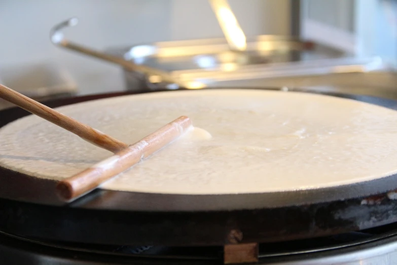 a pan sitting on top of a stove with a wooden stick sticking out of it, a picture, hurufiyya, sea of milk, white wax, round-cropped, turntables